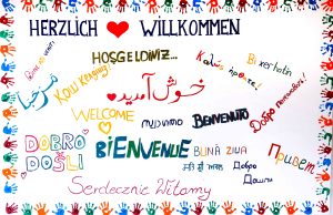 Gemaltes Schild: "Herzlich willkommen" in vielen Sprachen